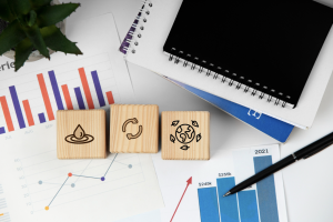 Wooden blocks with icons representing wellness, connectivity, and global health, surrounded by financial charts and graphs, illustrating key concepts in revenue cycle management for behavioral health providers in 2025.